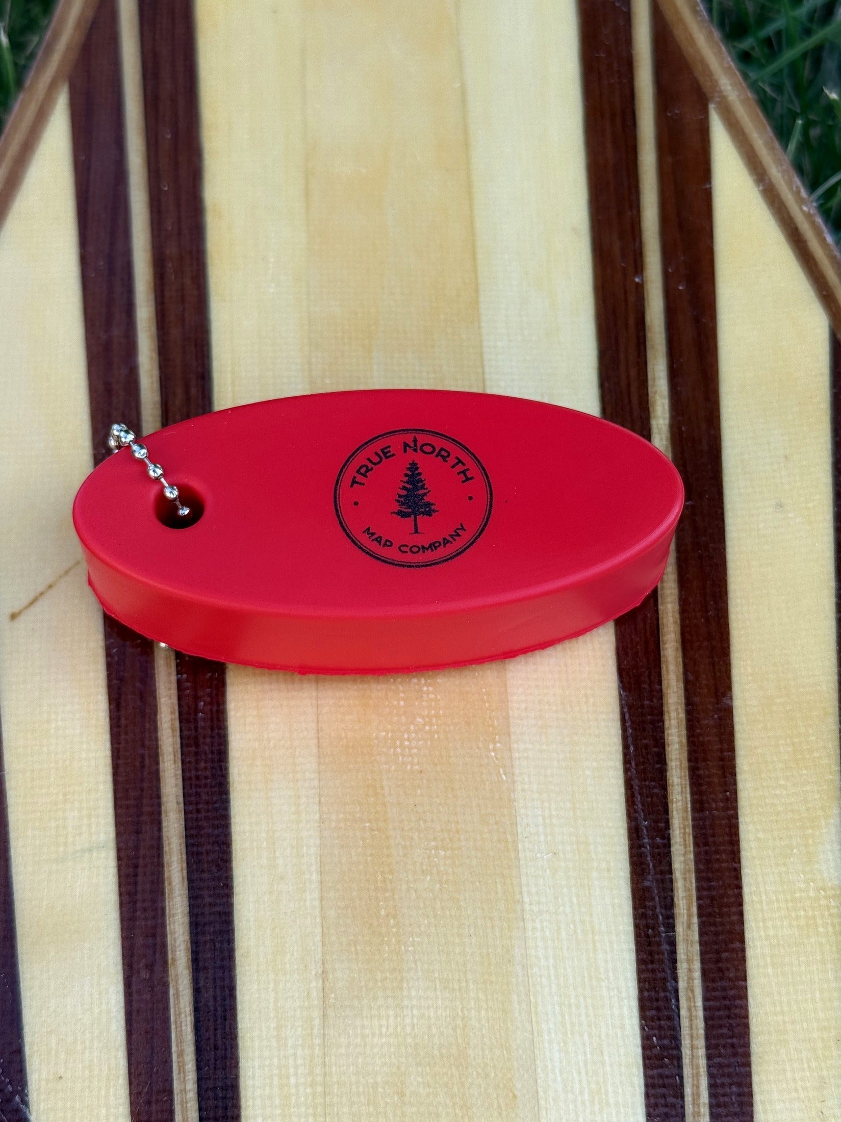 Close-up of the True North Map Co. floating keychain on a canoe paddle